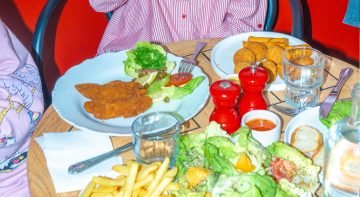 Schnitzel met garnering, friet, salade, bitterballen en sauzen op een houten tafel in eetcafé 't Meisje